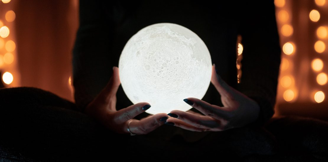 Illuminated crystal ball held in hands
