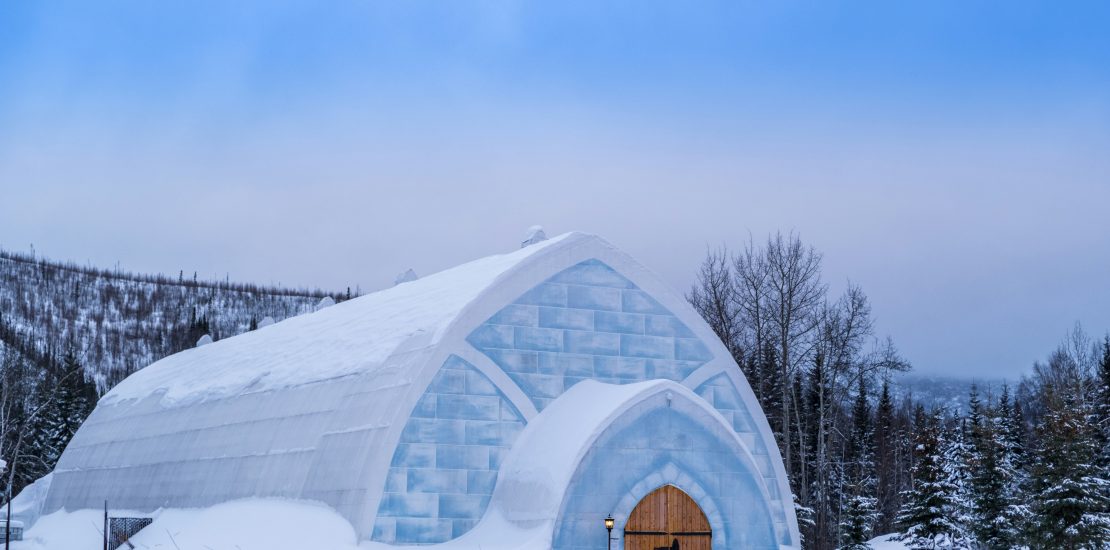 An igloo or ice house with a wooden door on a clear, snowy day.