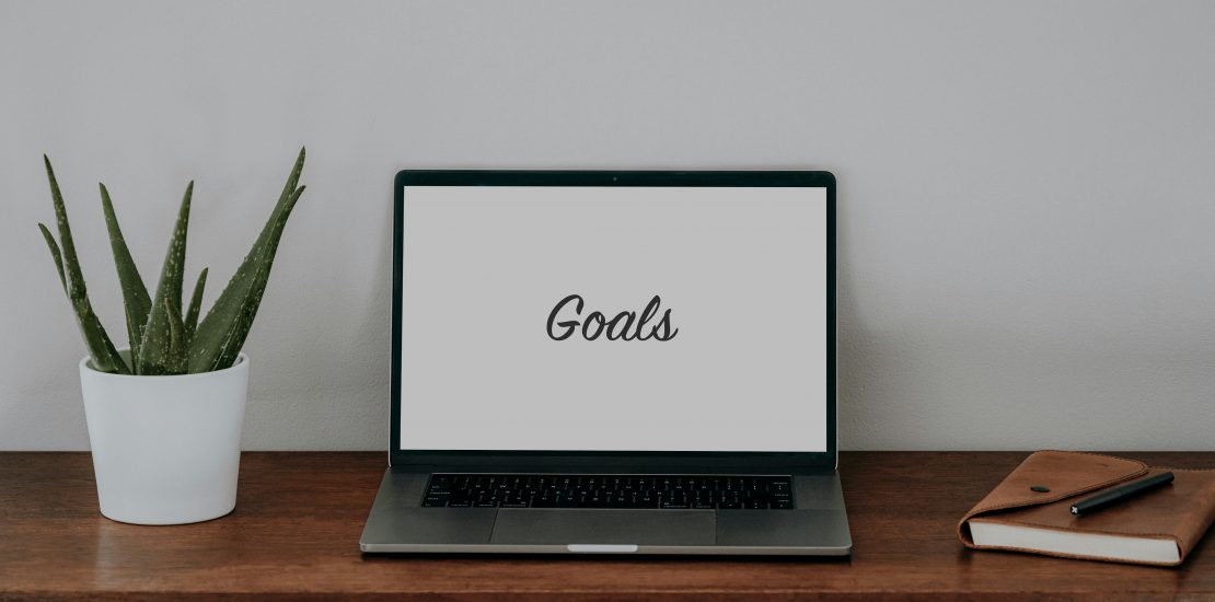 image of a laptop on a desk with the word "Goals" written on a white screen".