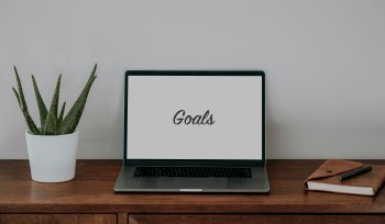 image of a laptop on a desk with the word "Goals" written on a white screen".