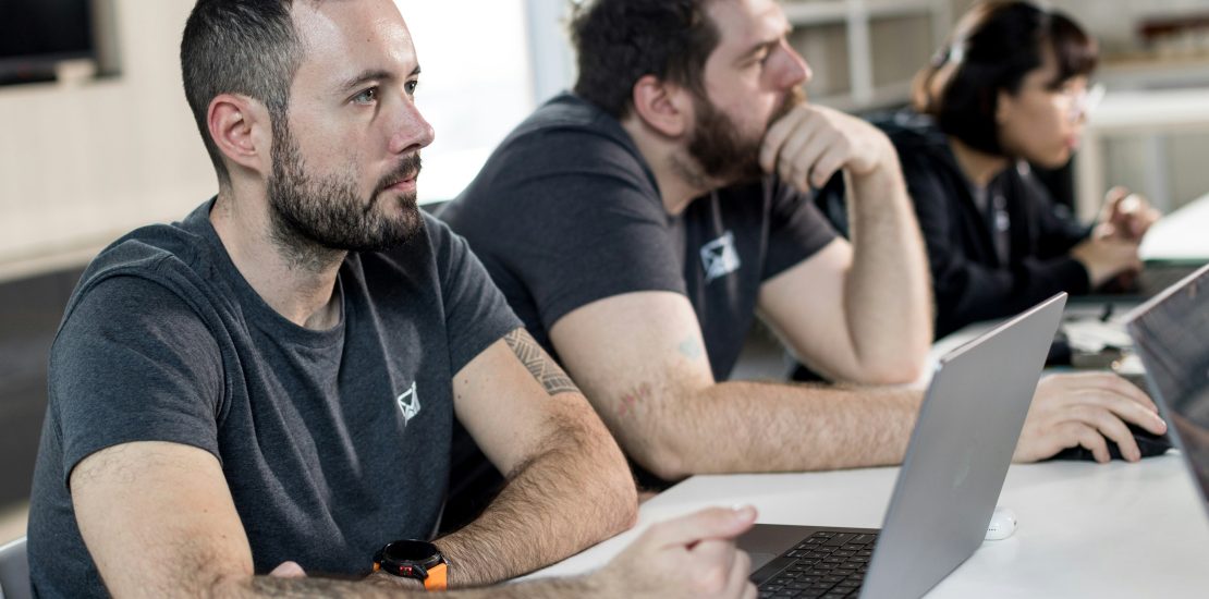 Two white male employees working at laptops in an office