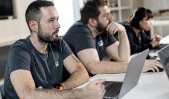 Two white male employees working at laptops in an office
